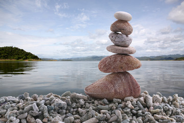 Balance stone on pile rock with river background.