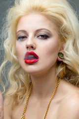 Portrait of young beautiful blond  woman with red lips  in the studio in a beautiful dress smoking a cigarette
