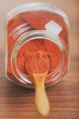 Paprika spice in glass jar with wooden spoon