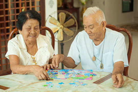 Asian couple senior playing with a jigsaw puzzle at home