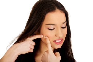 Teenage woman squeezing pimple.