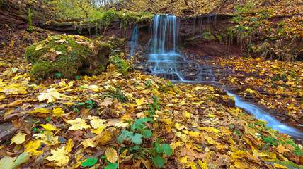 Fototapeta na wymiar A magical landscape with a waterfall in the autumn forest (harmo