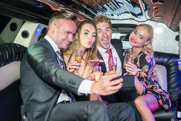 Excited male and female friends with champagne flutes taking sel