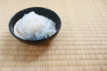Shirataki noodles in black plate placed on Japanese traditional Tatami flooring mat