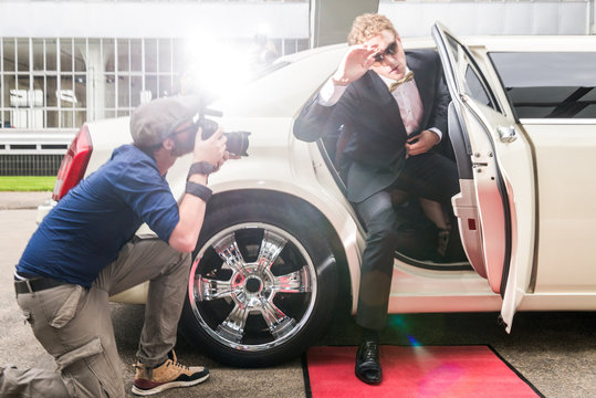 Young male celebrity hiding his face from paparazzi as he disemb