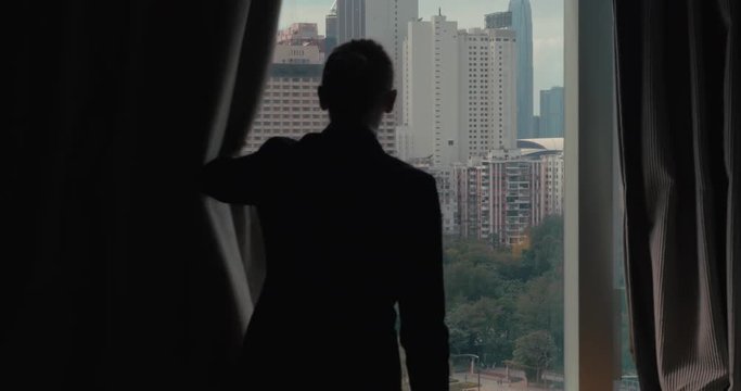 Clip of woman silhouette opening window curtains separately every side on the view of Hong Kong, China