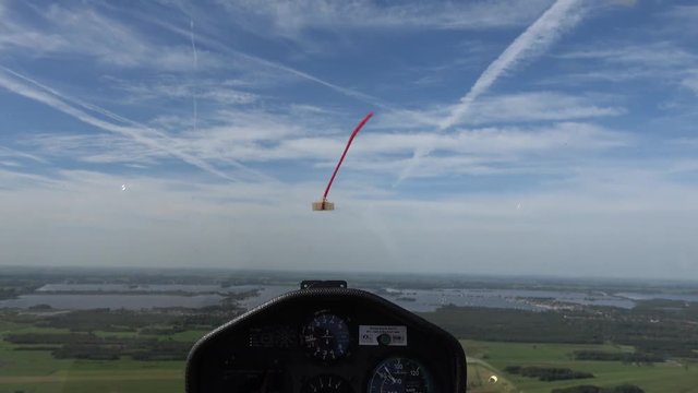 Cockpit point of view POV footage in modern glider sailplane flying in straight line towards lake showing instrument panel with gauges reading altitude airspeed ascending speed beautiful day blue sky