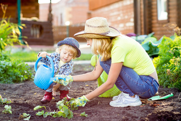 Child boy helps to mother working in the garden
