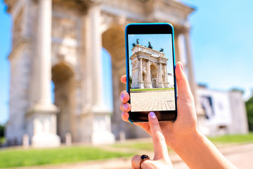 Holding phone with photo of triumphal arch in Milan city.