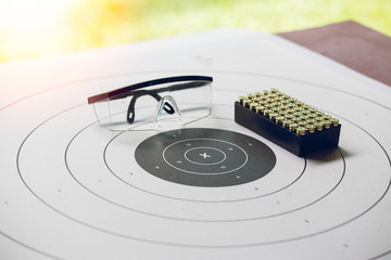 paper shooting target with bullet and protection glasses