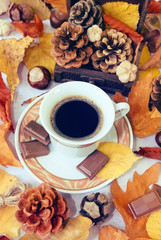 Autumn Cup of black coffee, chestnuts, pine cones, chocolate and autumn leaves. Autumn background. Autumn scene. Coffee and autumn leaves. Fall background.
