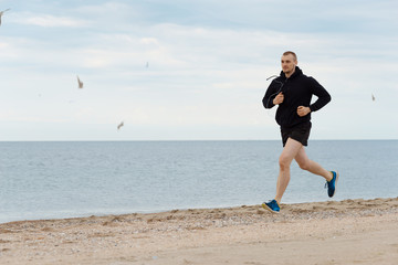 Молодой мужчина бегает по берегу моря