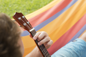 Fototapeta premium Detail of man relaxing on a hammock and playing ukulele