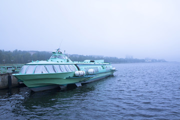 Fototapeta na wymiar Passenger hydrofoil boat on the docks of Onego lake in foggy weather, Petrozavodsk, Karelia, Russia.