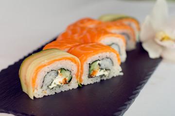 Salmon and cucumber sushi roll on slate textute close up