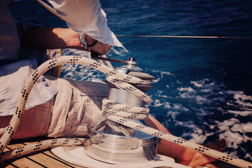 Sailing crew member pulling rope on sailboat
