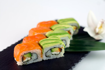 Salmon sushi and avocado sushi on black slate close up