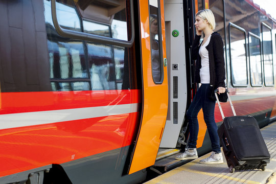 Young Woman With Wheeled Luggage Boarding Train