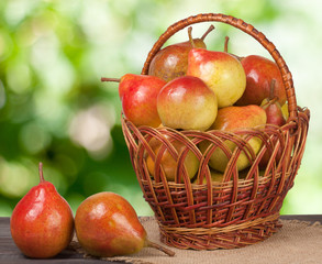 pears in a wicker basket on wooden table with blurred background