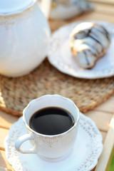Obraz na płótnie Canvas Cup of tasty coffee with a sweet croissant