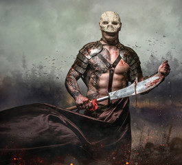 Male in the skull mask holds sword in the dust batterfield backg