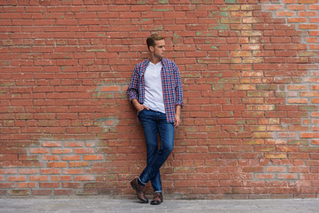 Handsome guy standing near brick wall - Powered by Adobe