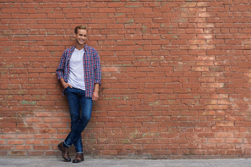Handsome guy standing near brick wall - Powered by Adobe