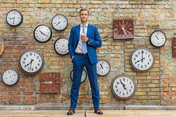 Man in suit standing near wall with clocks