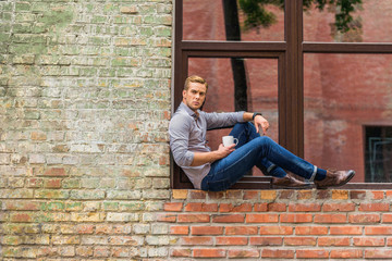 Handsome man drinking coffee outside of office building