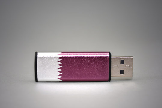 usb flash drive with the national flag of qatar on gray background.
