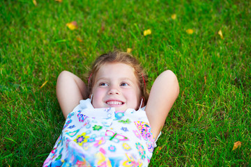 little girl smiling and resting on the grass a summer day