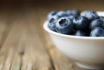 Blueberries in a tea Cup on a wooden table.