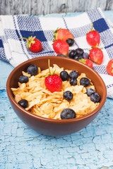 Portion of corn flakes in the bowl with different ripe berries