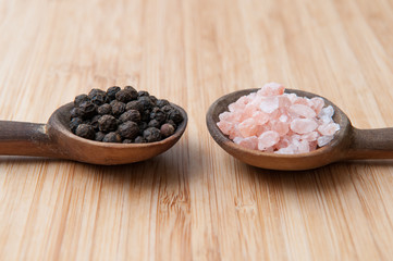 Salt and pepper seasonings of pepper corns and rock salt on wood