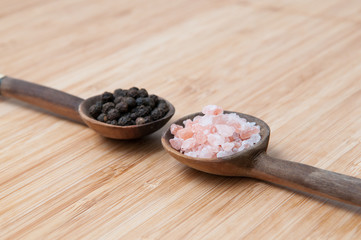 Salt and pepper seasonings of pepper corns and rock salt on wood