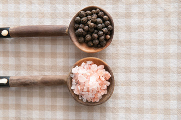 Salt and pepper seasonings of pepper corns and rock salt on wood