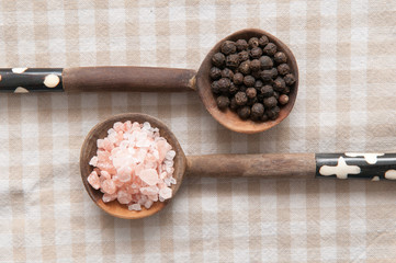 Salt and pepper seasonings of pepper corns and rock salt on wood