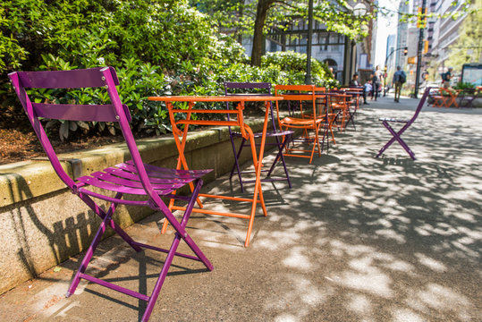 Orange And Purple Colored Chairs In Downtown Park With People Walking In Vancouver, Canada