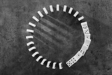 Circle of dominoes standing on gray background