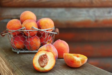Fresh peaches in basket on wooden background