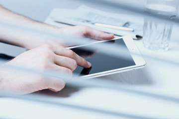 Fototapeta premium Man holding tablet in hands. View through blinds