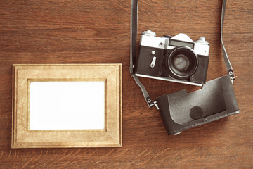 Vintage camera and frame on wooden background