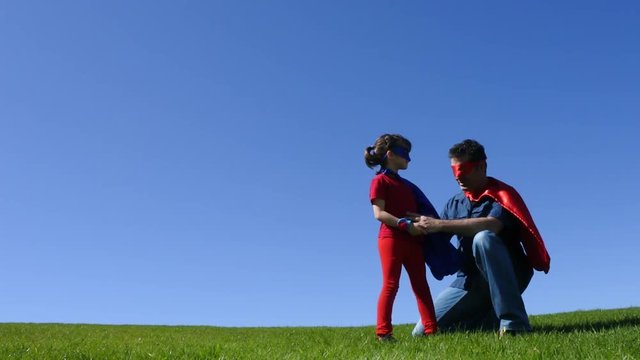 Superhero father show his daughter how to be  a superhero against blue sky background with copy space. concept photo of Super hero, childhood, imagination, fatherhood and parenthood. Real people