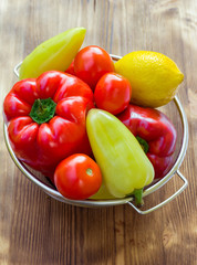 Vegetable still life of peppers, tomatoes, lemon in sieve bowl
