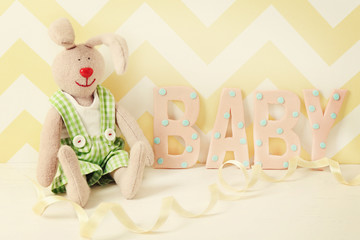 Word "Baby" with toy on bright background