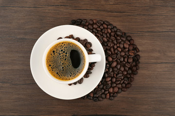 Cup of coffee with beans on wooden background