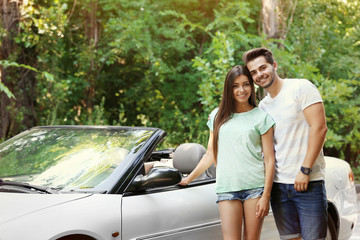 Beautiful couple standing near car on road