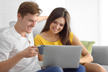 Beautiful couple surfing internet on laptop at home