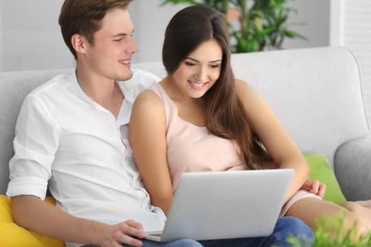 Beautiful couple surfing internet on laptop at home