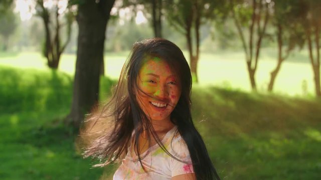 closeup Asian beautiful girl having fun in the Park with the colors of Holi,slow motion